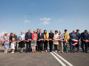 Symboliczne otwarcie drogi - zdjęcie przedstawia uczestników wydarzenia przecinających wstęgę