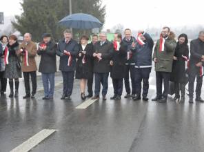 Symboliczne otwarcie drogi - zdjęcie przedstawia uczestników wydarzenia przecinających wstęgę